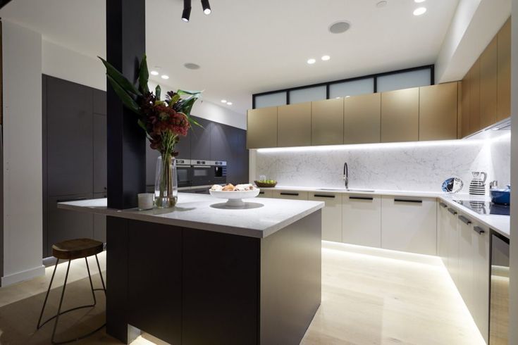 a modern kitchen with an island in the middle and white countertops on both sides