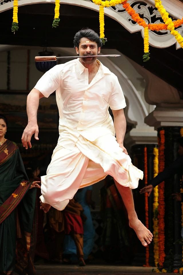 a man dressed in white is performing on stage with his legs stretched out and feet spread wide