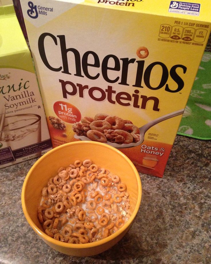 cereal in a bowl next to a carton of cheerios protein on a counter