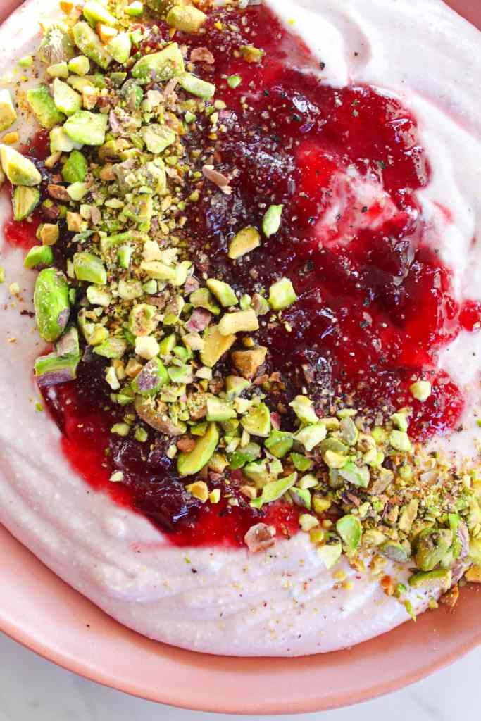 a bowl filled with yogurt topped with nuts and cranberry sauce