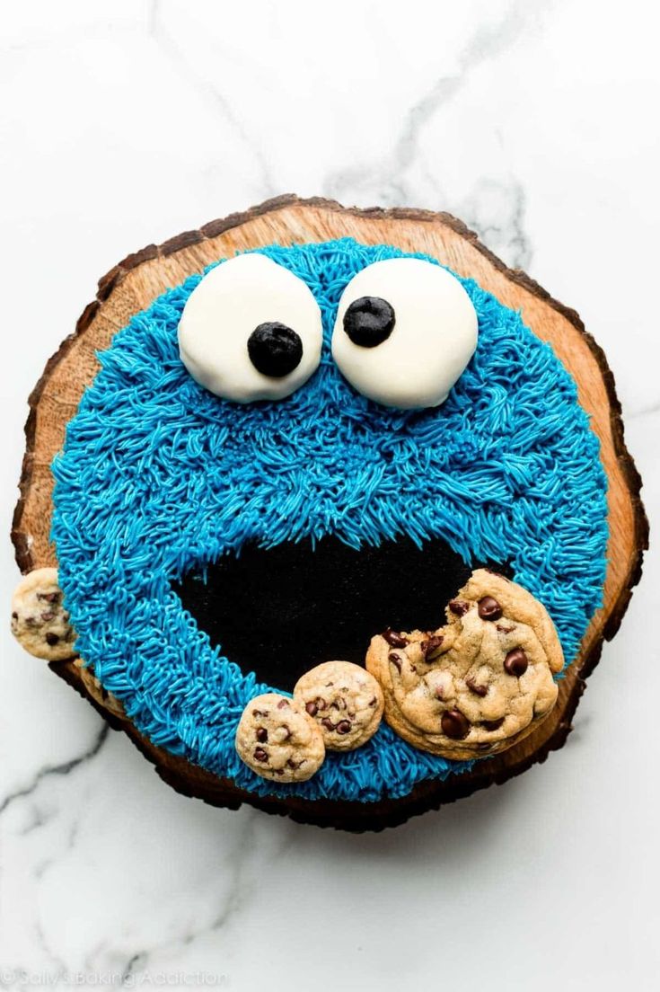 cookie monster cake with eyes and cookies on the top, sitting on a wooden slice