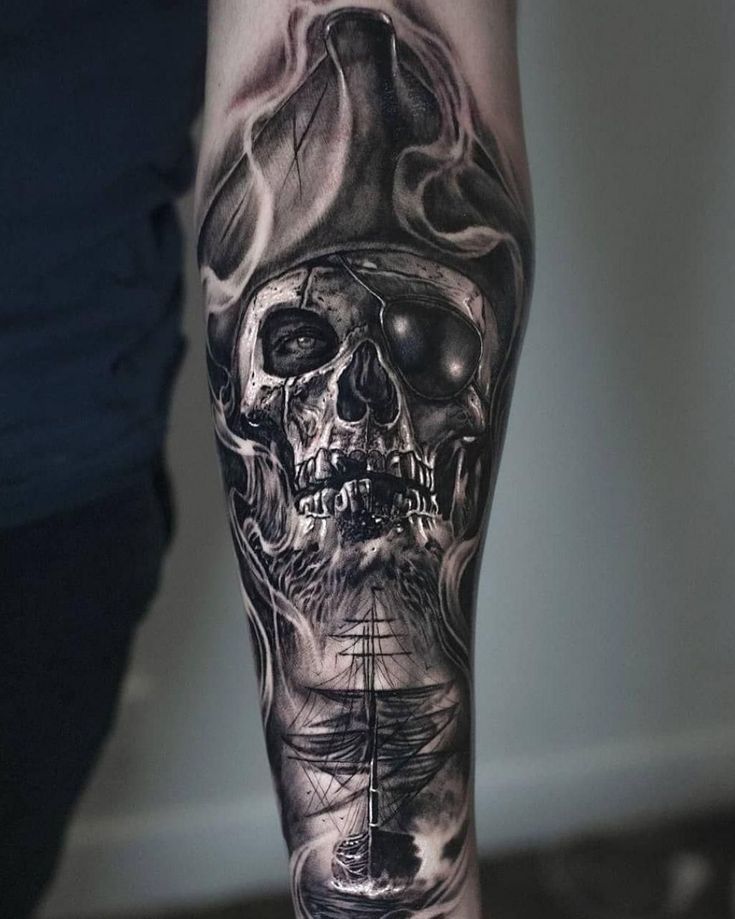 a man's arm with a skull and ship tattoo on it