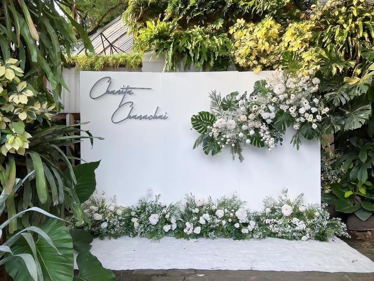 a white sign with flowers and greenery on it