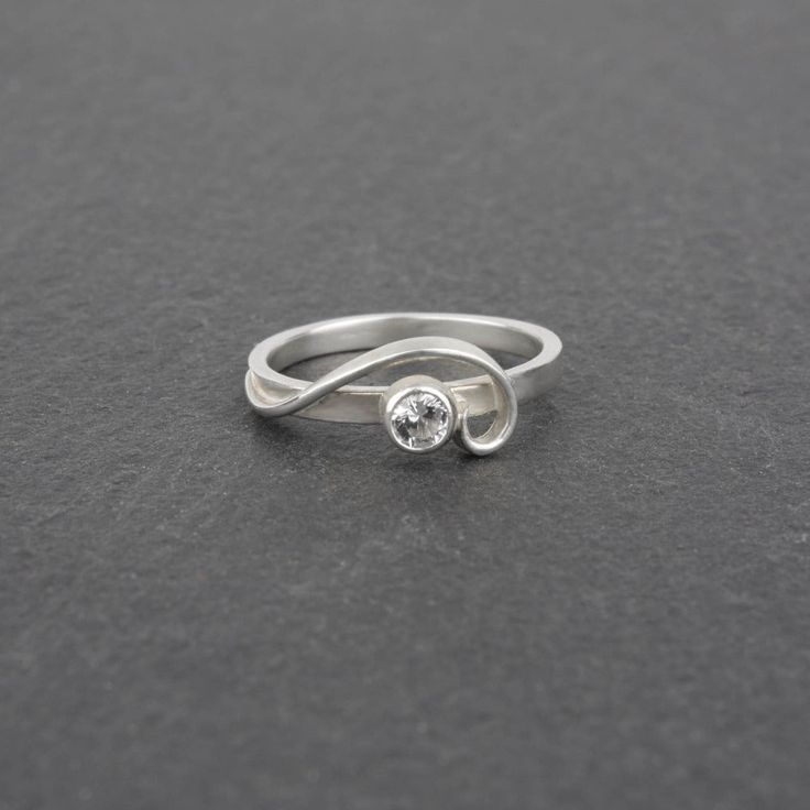 The so-called "whiplash line" is one of the defining hallmarks of the Art Nouveau style. Here, the whiplash curves in a graceful arabesque around a sparkling gemstone and entwines around your finger. The Arabesque Ring is dainty and elegant when worn alone; but this slender stacking ring is designed to nestle closely with one or more accompanying bands. This sparkly white sapphire and sterling silver ring is handcrafted and made to order. Wear it by itself, or customize a stack of skinny bands a Modern Twist Diamond White Jewelry For Formal Occasions, Formal Diamond White Jewelry With A Modern Twist, Minimalist Curved Wedding Jewelry, Elegant Adjustable Gemstone Stackable Rings, Modern Diamond Promise Ring, Formal Stackable Rings With Modern Twist, Modern Twist Sterling Silver Jewelry, Adjustable Stackable Rings With Modern Twist For Wedding, Modern Twist Stackable Adjustable Rings For Formal Events