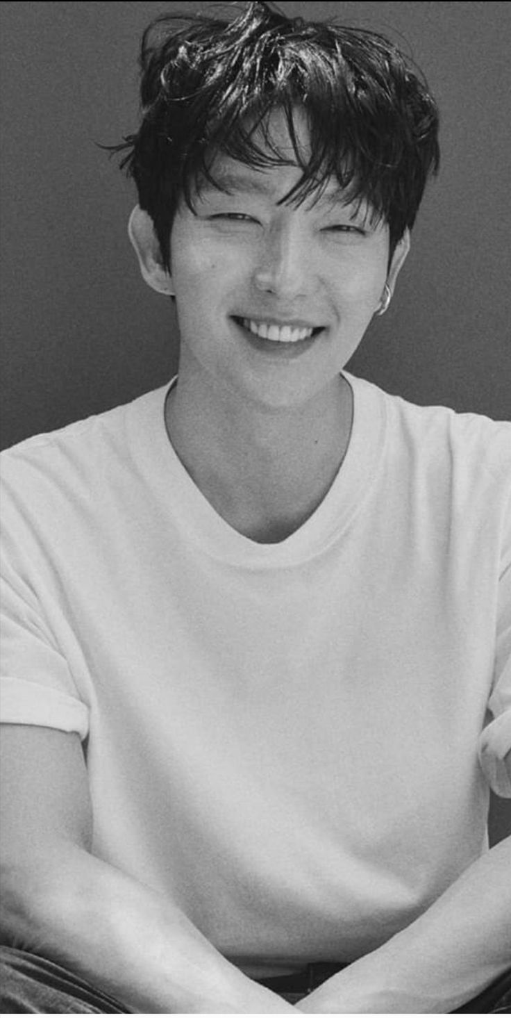 black and white photo of a young man smiling at the camera with his arms crossed