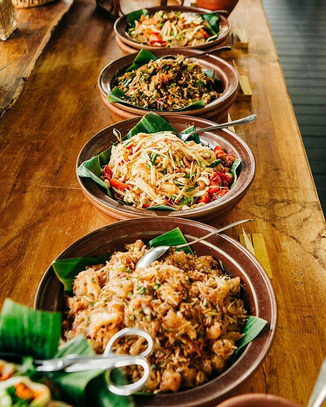 a long wooden table topped with lots of plates filled with different types of food on top of it