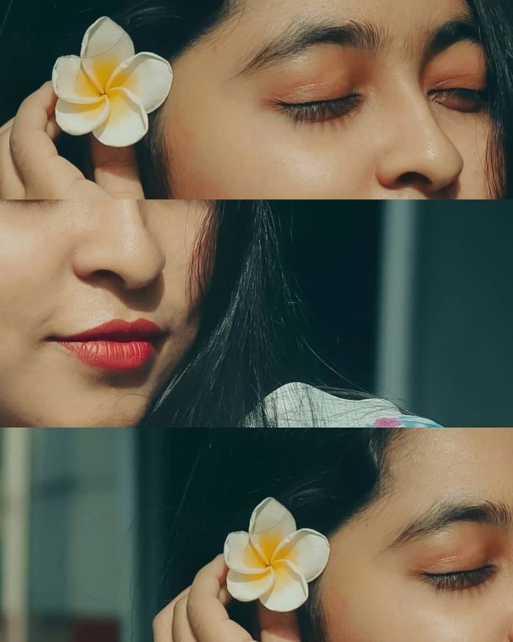 a woman with her eyes closed and flowers in her hair being held up to her face