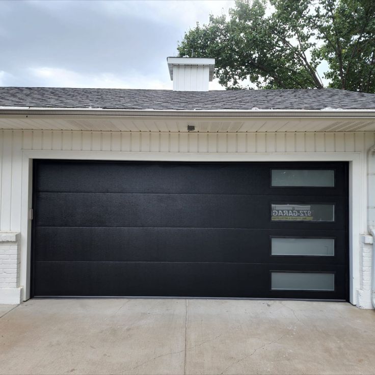 a black garage door in front of a white house