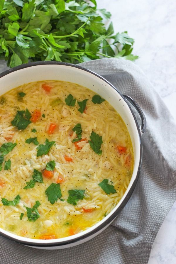 a white bowl filled with soup and garnished with cilantro, carrots and parsley