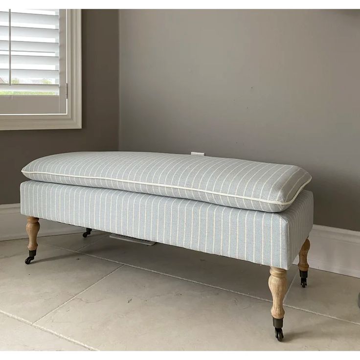 an upholstered bench sitting in front of a window