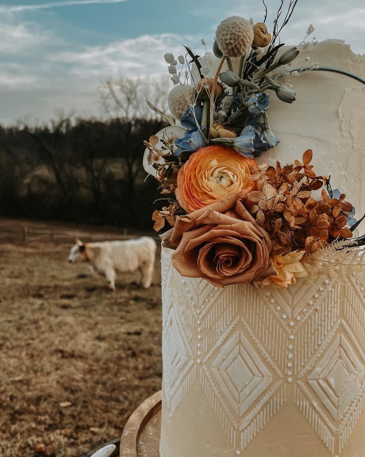 a close up of a cake with flowers on it in the middle of a field