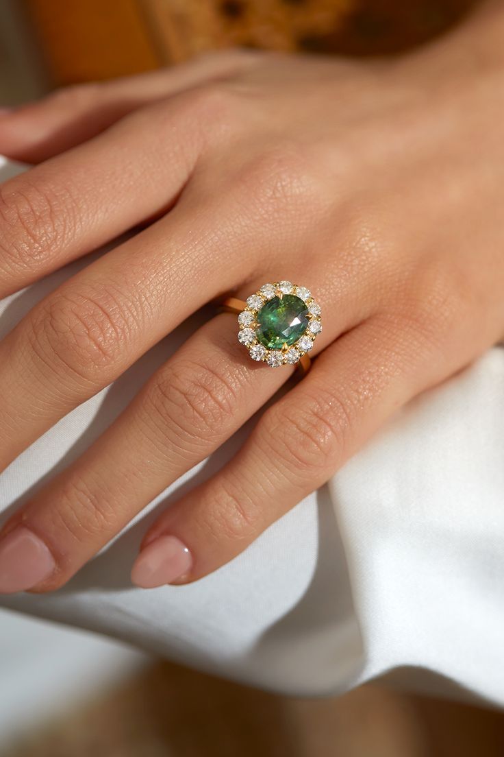 a woman's hand with an emerald and diamond ring