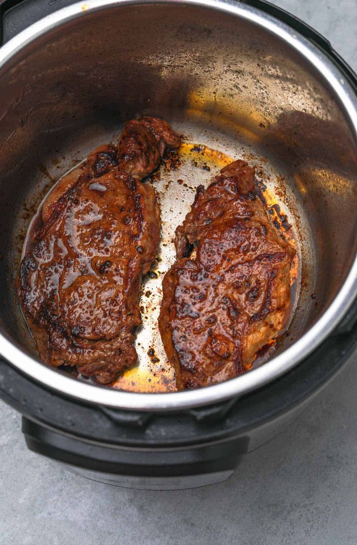 two pieces of meat are cooking in an electric pressure cooker