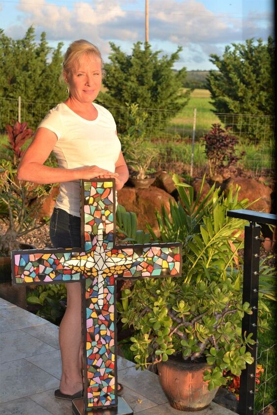 a woman standing next to a cross on top of a wooden table with potted plants