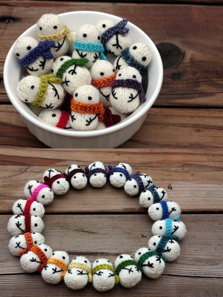 a white bowl filled with lots of small knitted balls on top of a wooden table