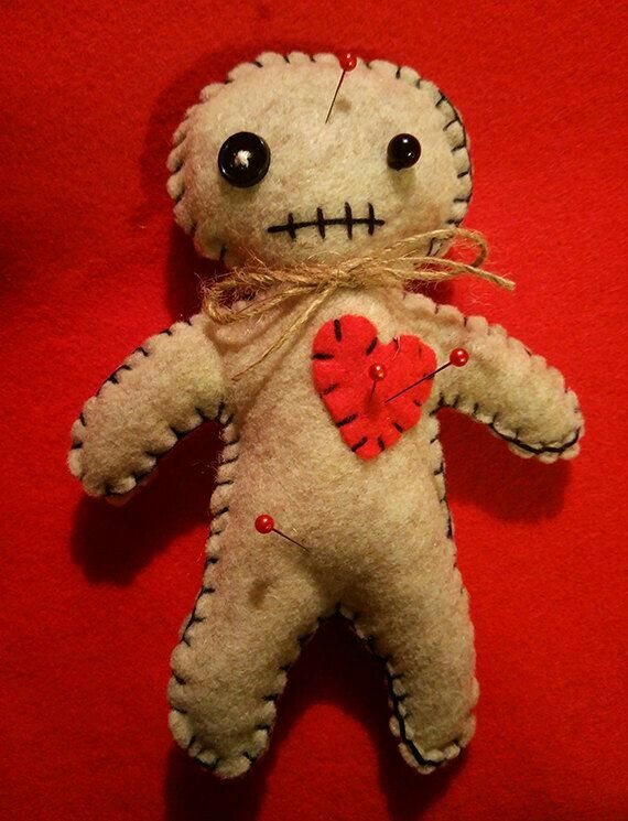 a voodoo doll with a red heart on it's chest sitting on a red surface