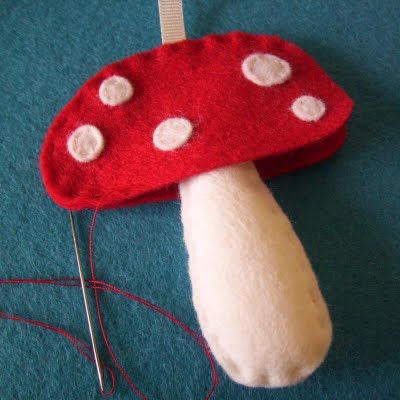 a red mushroom with white dots on it is hooked up to a needle and thread