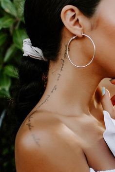 a woman wearing large hoop earrings with writing on it