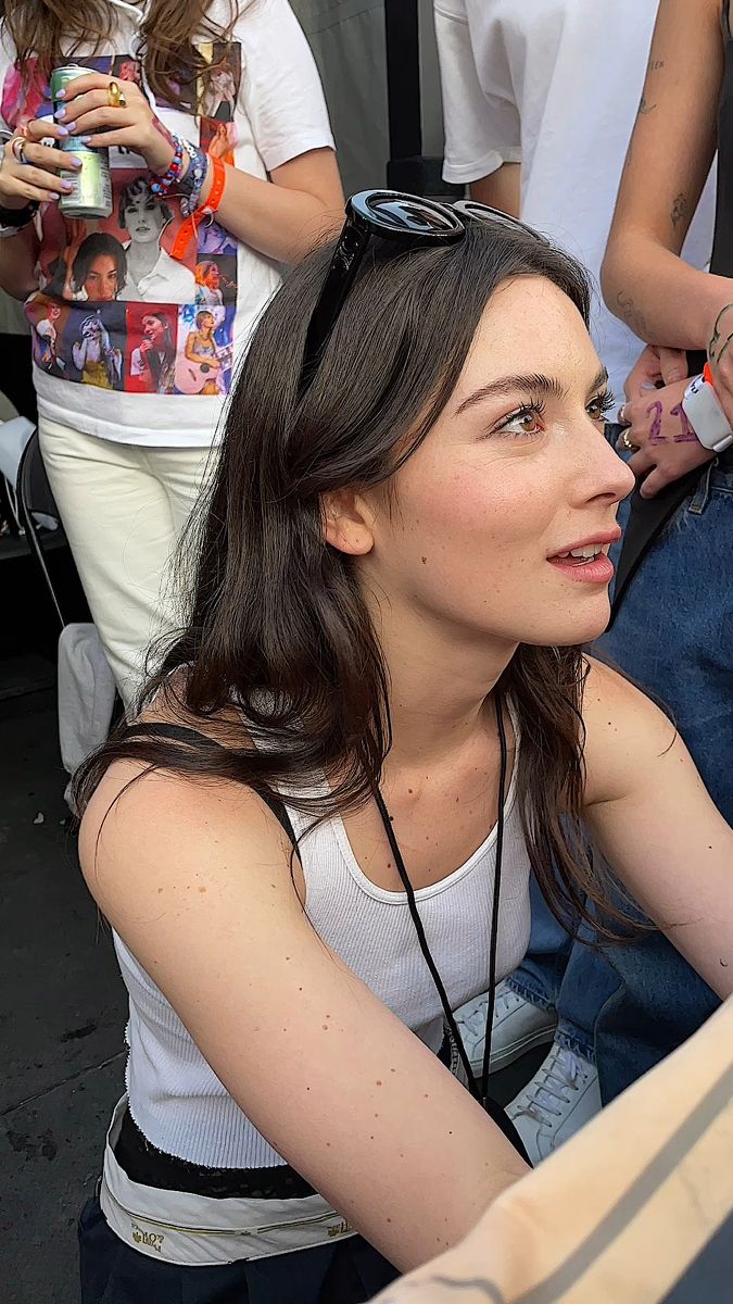 a woman sitting in front of a cake on top of a table next to other people