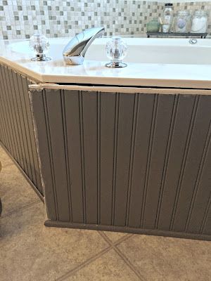 a bath tub sitting on top of a tiled floor next to a wall mounted faucet