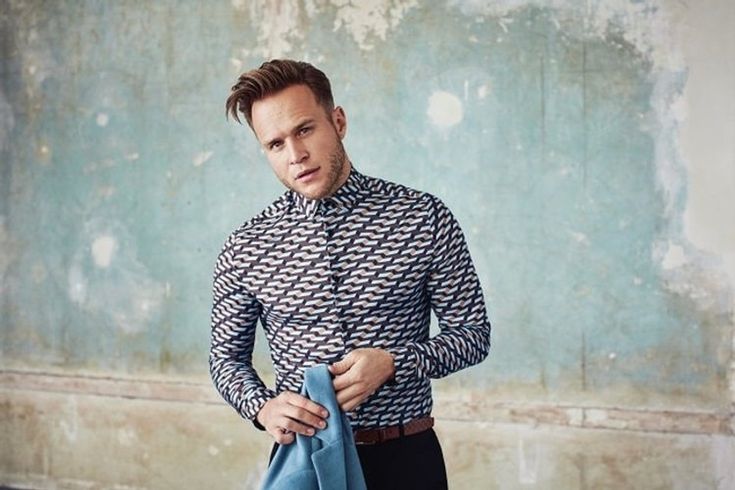 a man is standing with his hands in his pockets and wearing a patterned shirt that has an arrow pattern on it