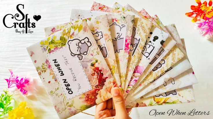 a person is holding up some cards with hello kitty on them and flowers in the background