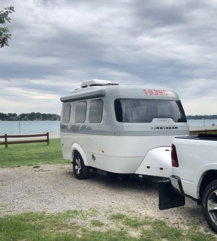 an rv parked on the side of a road next to a body of water with clouds in the sky