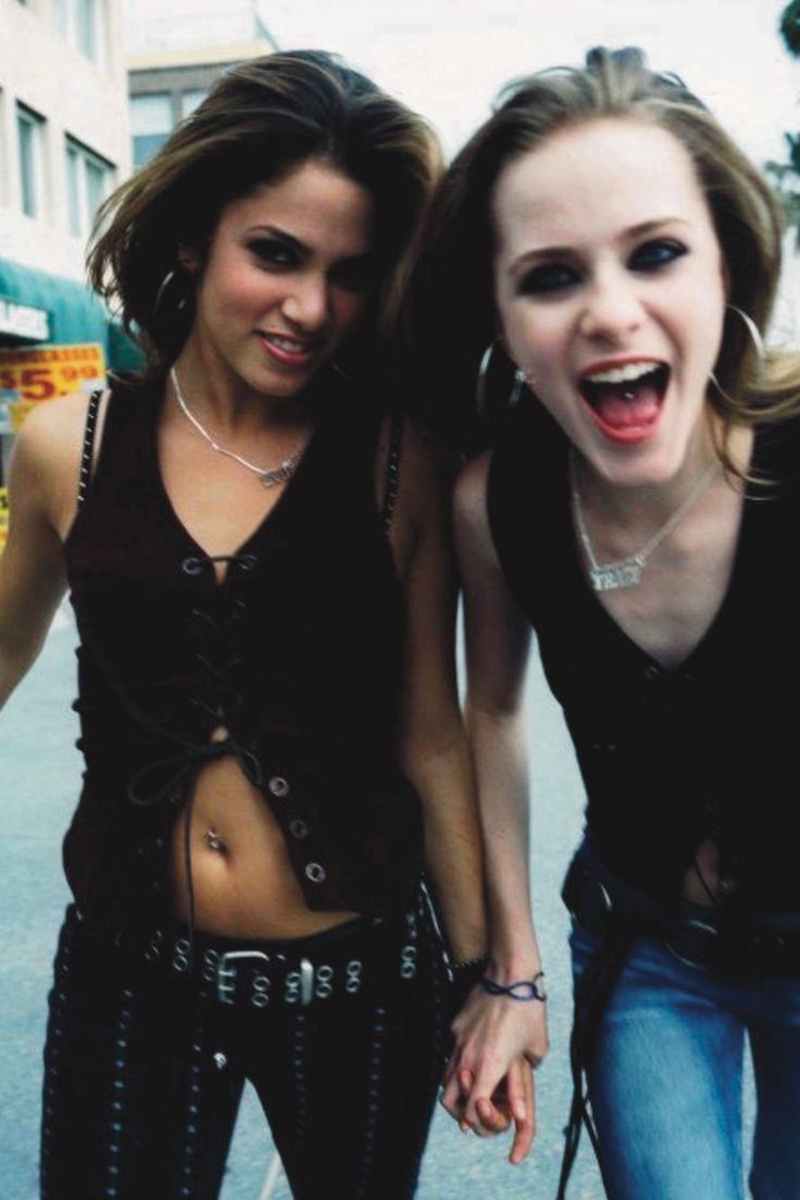 two young women standing next to each other in the street with their mouths open and one holding her hand out