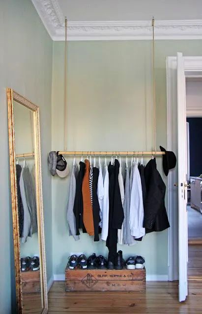 an open closet with clothes and shoes hanging on the wall next to a large mirror