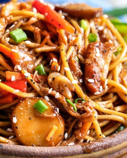 a close up of a plate of food with noodles and vegetables in it on a table