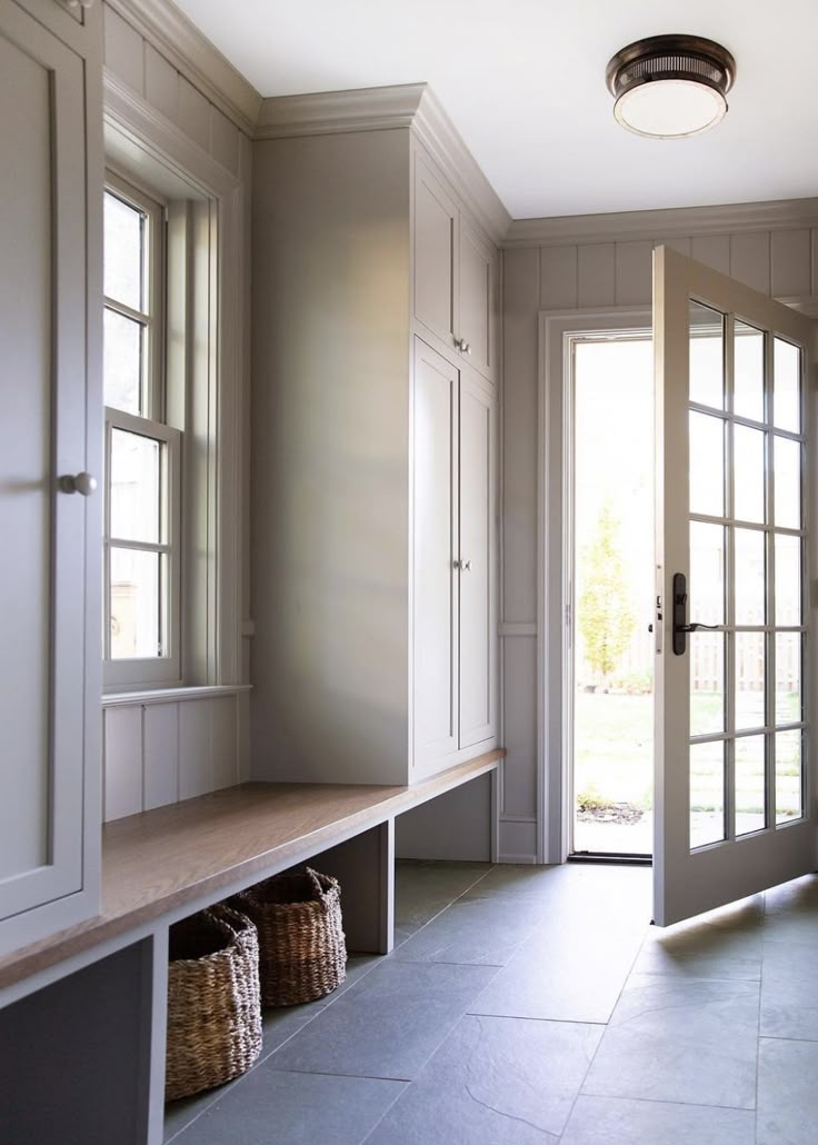 an empty entryway with two large doors and baskets on the bench next to it