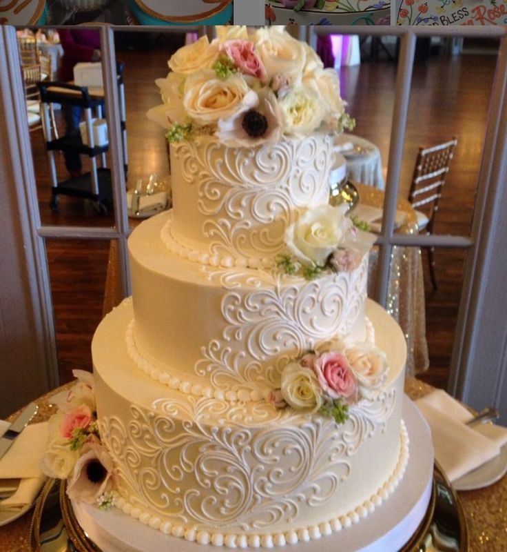 a three tiered wedding cake with flowers on top