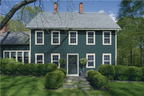 a large blue house with white trim and two story windows on the front of it