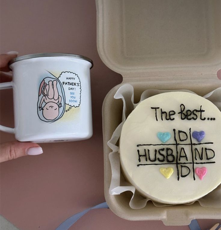 a cake in a box with writing on it next to a coffee mug