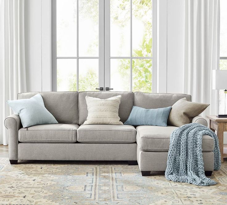 a living room scene with focus on the couch and pillows in front of the window