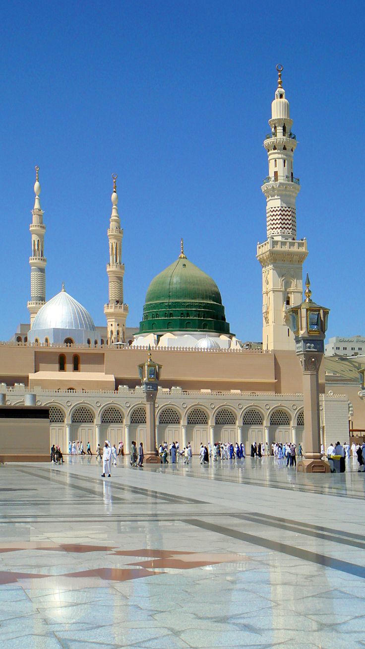 a group of people standing in front of a building with two green domes on it