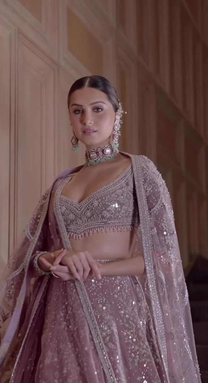 a woman in a purple lehenga standing next to some stairs and wearing jewelry