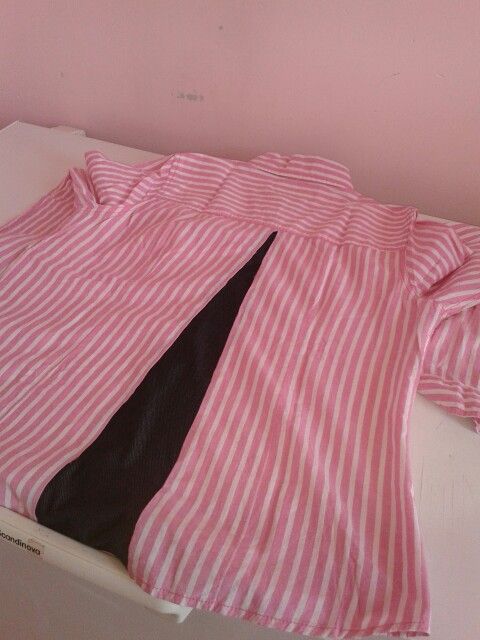 a pink and white striped shirt laying on top of a bed