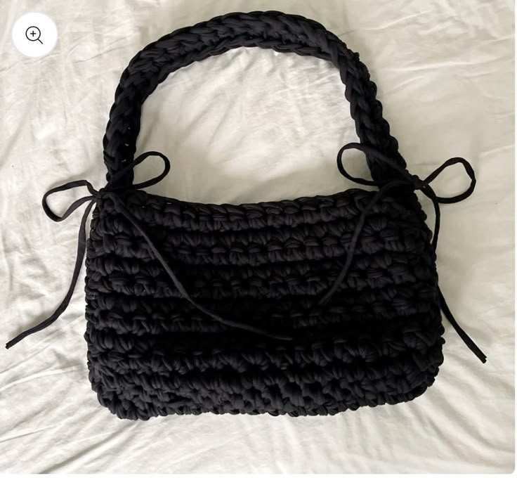 a black purse sitting on top of a bed