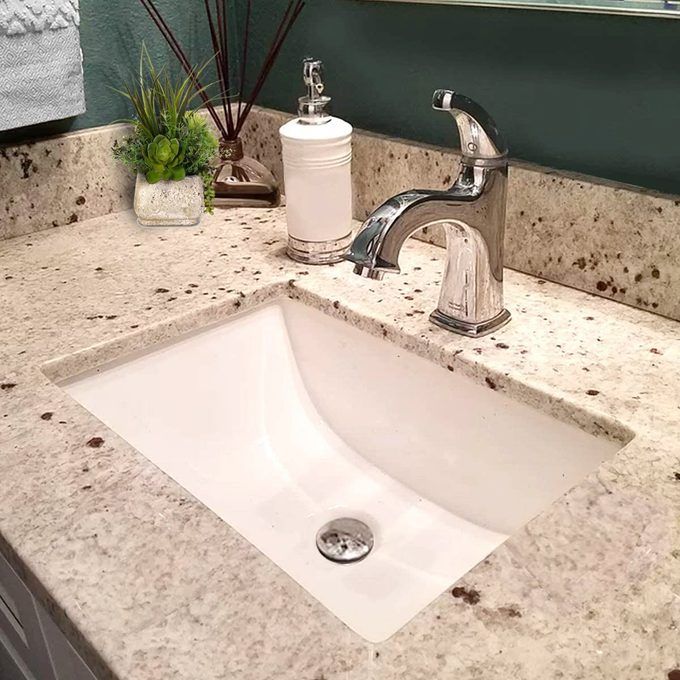 a white sink sitting under a bathroom mirror next to a faucet and soap dispenser