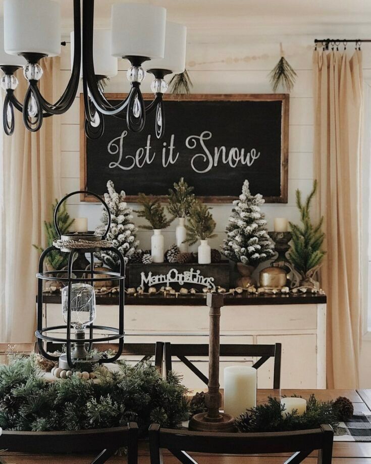 a dining room table decorated for christmas with candles and greenery on the side, next to a sign that says let it snow