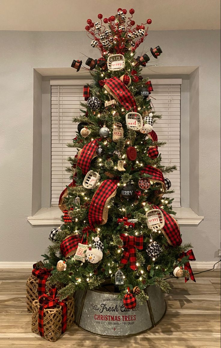 a christmas tree decorated with red and black plaid ribbon, ornaments, and tin cans