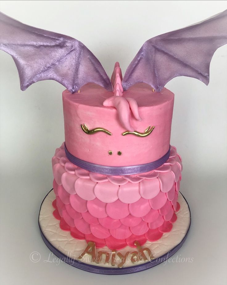 a pink and purple cake with a dragon on top