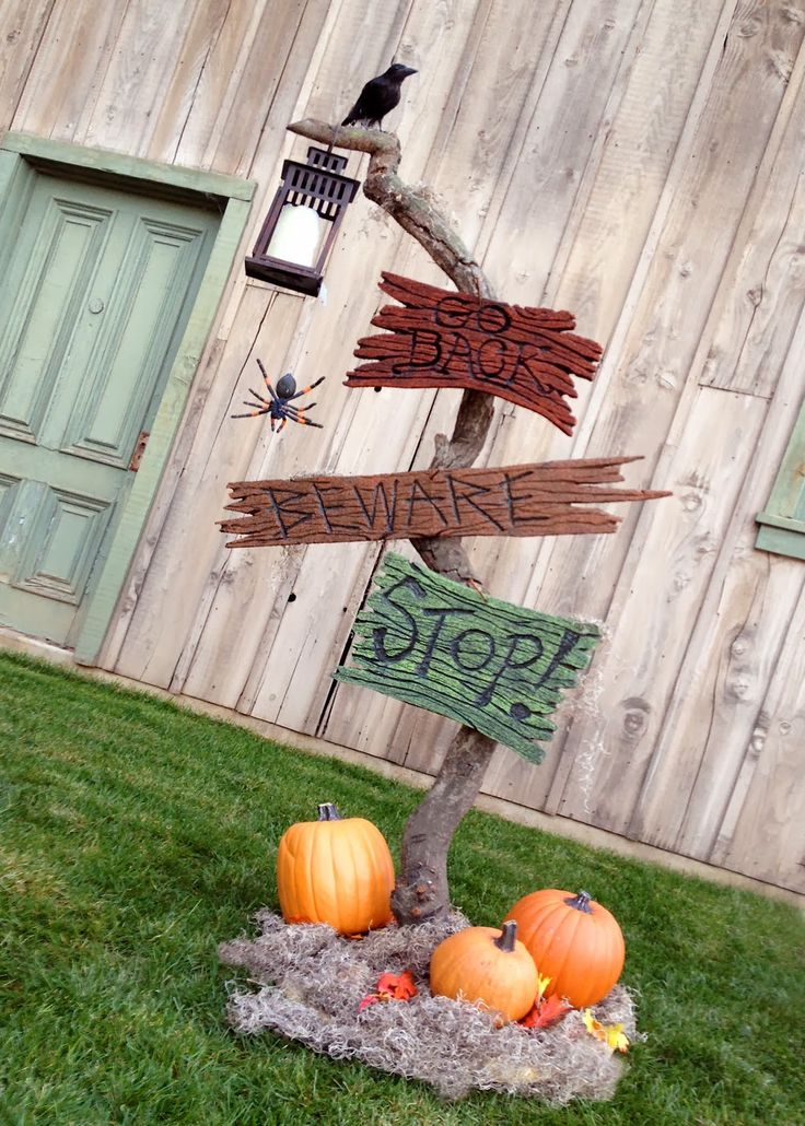 a wooden sign sitting on top of a grass covered field next to pumpkins and a bird