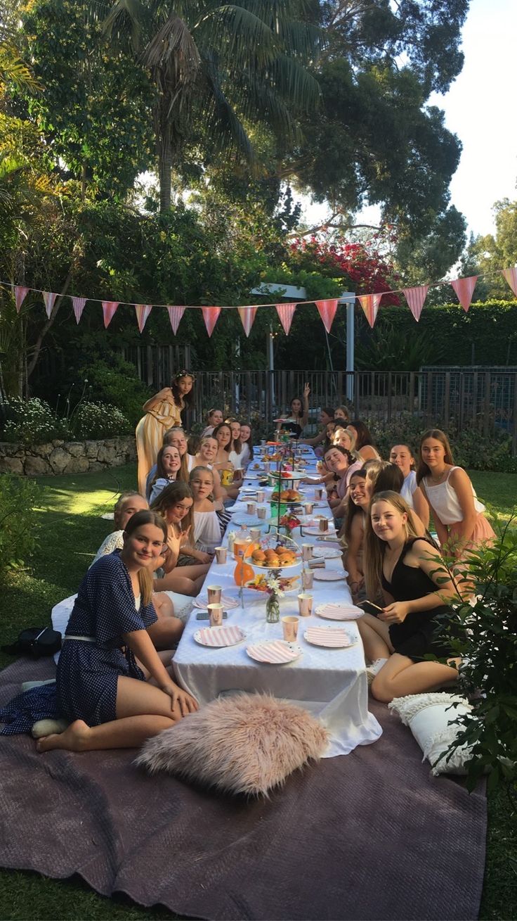 a group of people sitting at a long table with plates and drinks in front of them