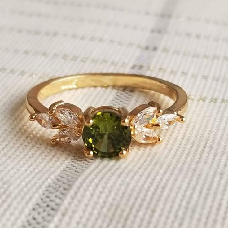 a close up of a ring with a green and white stone in it on a table