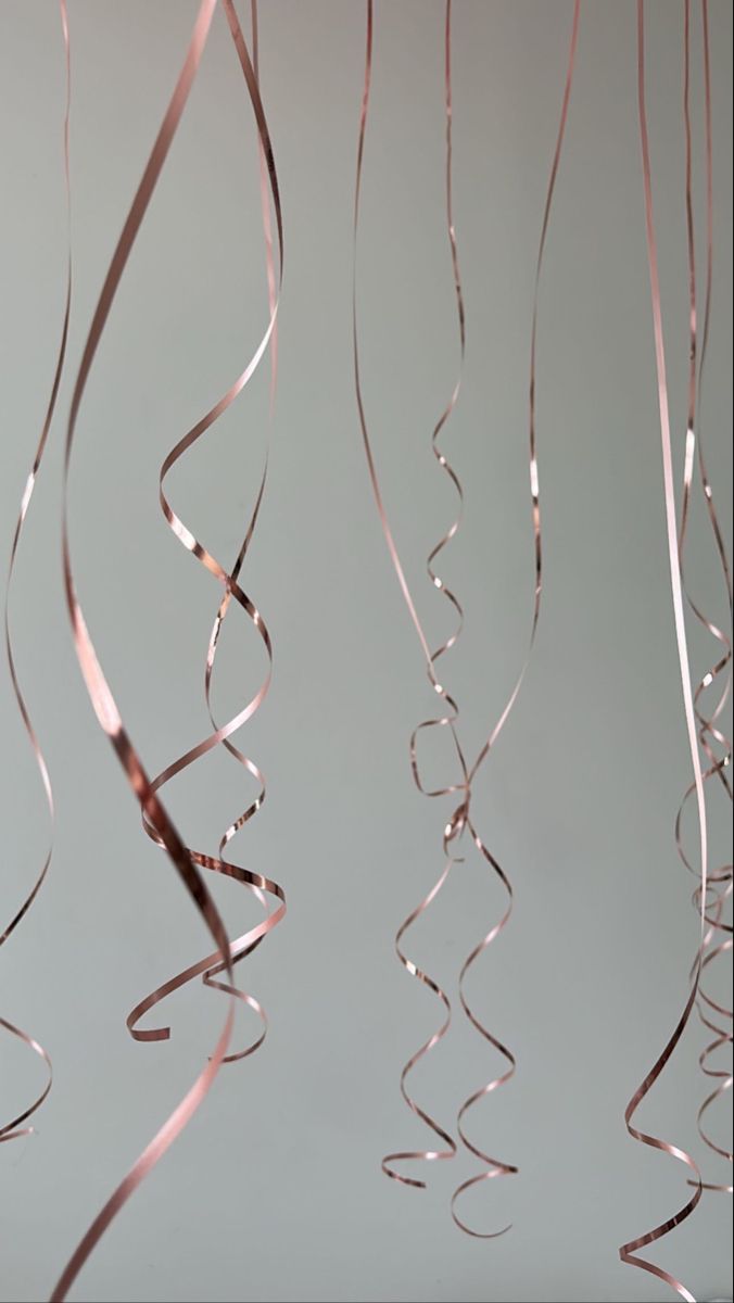 some pink streamers hanging from the ceiling in front of a gray wall and floor