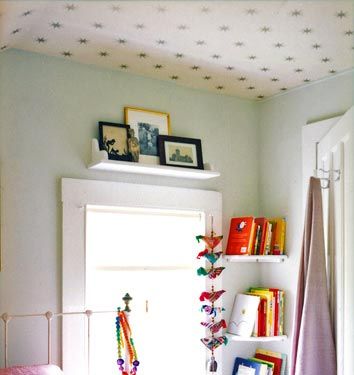 a bed room with a neatly made bed and a book shelf on the wall above it