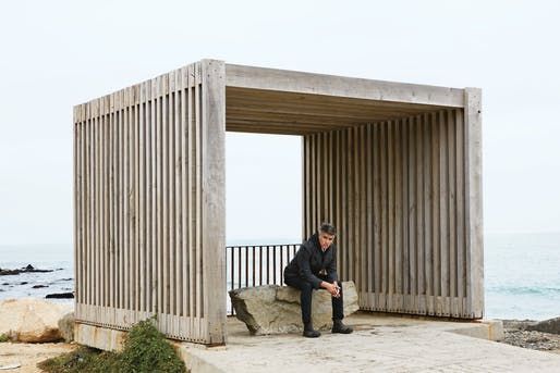 a man sitting on top of a cement structure next to the ocean