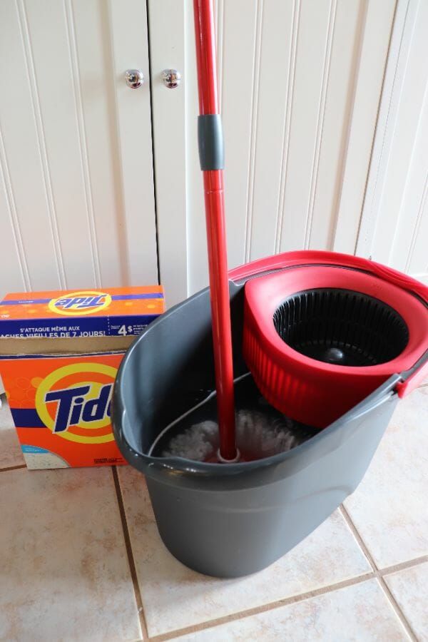 a mop and bucket sitting on the floor next to a box of cleaning supplies